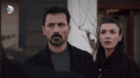a man and woman are standing next to each other in front of a building .