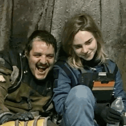 a man and a woman are laughing and sitting next to each other .