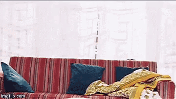 a red striped couch with blue pillows and a blanket