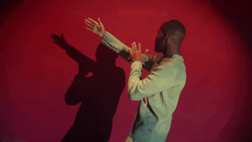 a man in a green sweater is dancing in front of a red background