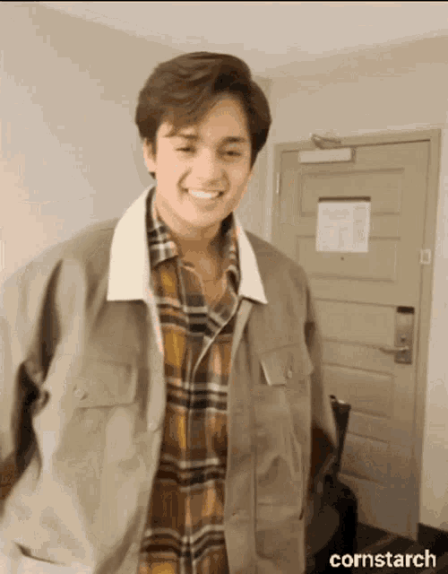 a man in a plaid shirt is smiling in front of a door that says cornstarch on the bottom