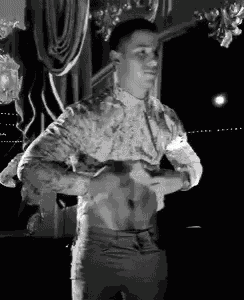 a man in a floral shirt is taking off his shirt in a black and white photo .