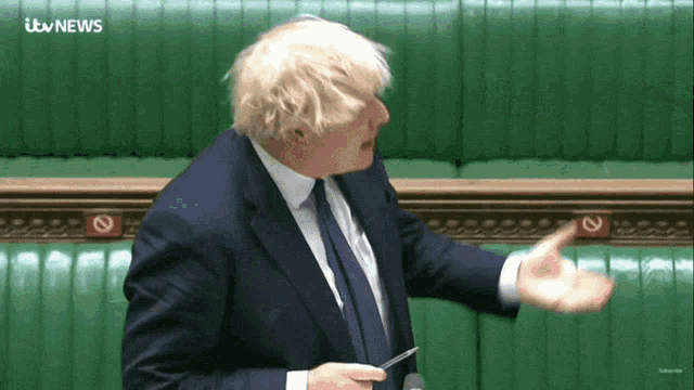 a man in a suit and tie is giving a speech in front of an itv news screen