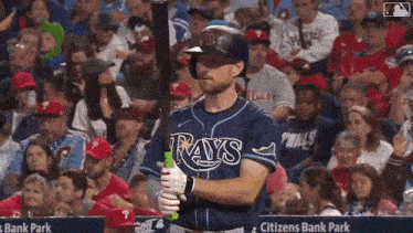 a baseball player in a rays uniform is holding a bat in front of a crowd .