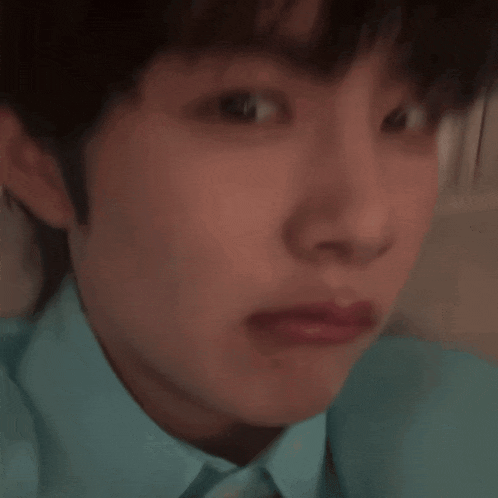 a close up of a young man 's face with a blue shirt on making a funny face .