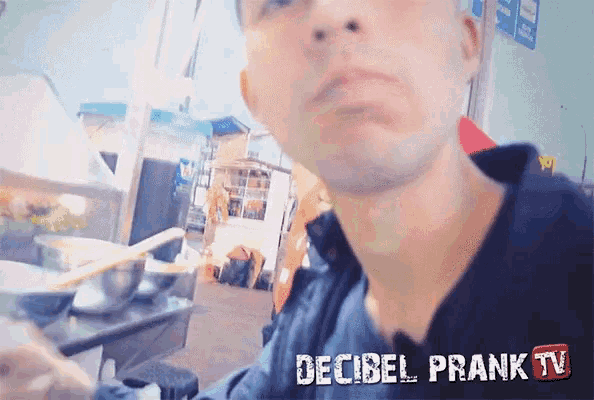 a man sitting at a table with the words decibel prank tv written below him