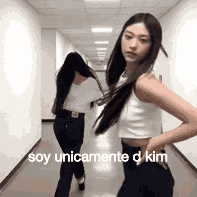 two women are dancing in a hallway with the words soy unicamente d kim in the corner .