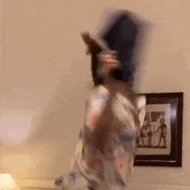 a person is standing in a room with a picture on the wall behind them .