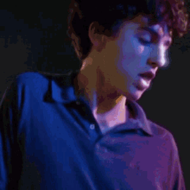 a close up of a man 's face with a blue shirt on