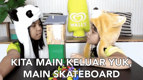 two girls wearing hats sitting at a table with the words kita main keluar yuk main skateboard below them