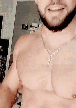 a man without a shirt is wearing a necklace with a cross on it