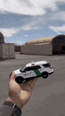 a hand holding a toy border patrol car