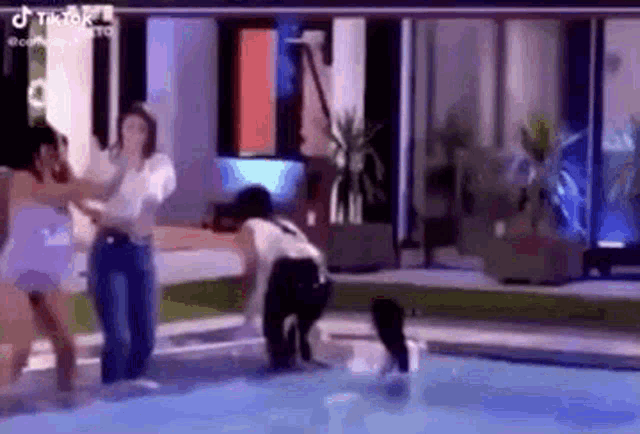 a group of people are standing in a pool .