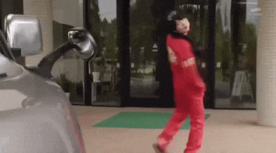 a person in a red jumpsuit is walking in front of a car .