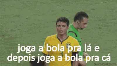 a soccer player in a yellow jersey is being tackled by a referee in a green shirt