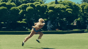 a person wearing a hat is running on a grassy field