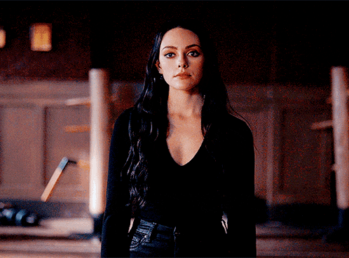 a woman in a black shirt stands in a dark room