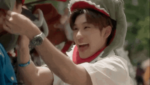a young man wearing a shark hat is laughing while holding another man 's hand .