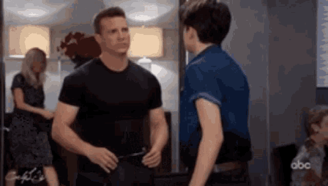 a man in a black shirt is standing next to a woman in a blue shirt .