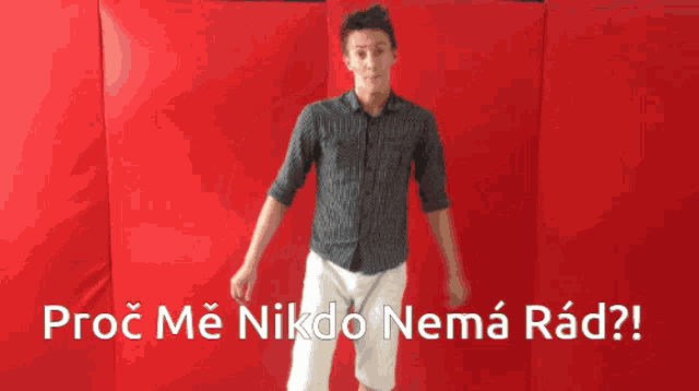 a man is standing in front of a red wall with the words proč me nikdo nemá rad below him