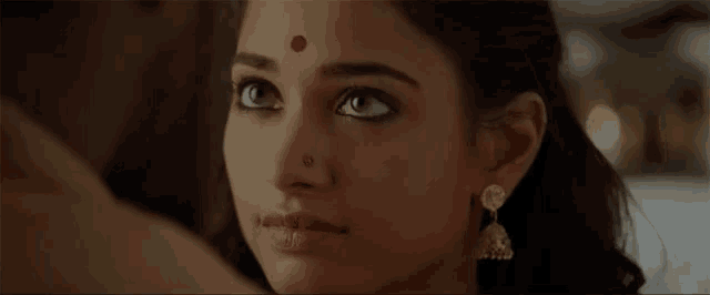 a woman with a red dot on her forehead looks at the camera .