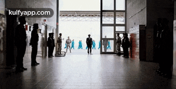 a group of people standing in a hallway with a sign that says kulfyapp.com on it