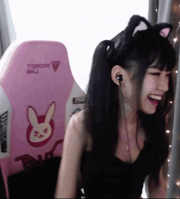 a woman wearing a cat ear headband sits in a pink chair