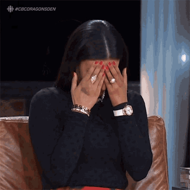a woman is covering her face with her hands while sitting in a chair ..