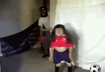 a little girl in a red shirt is standing next to a soccer ball