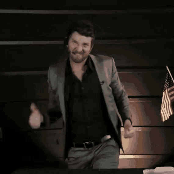 a man in a suit dancing in front of an american flag