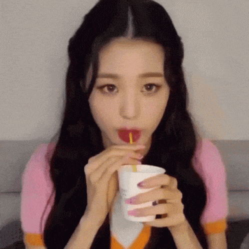 a woman is drinking from a cup through a straw .