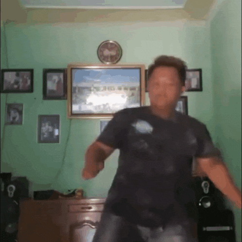 a man is dancing in a living room in front of a clock .