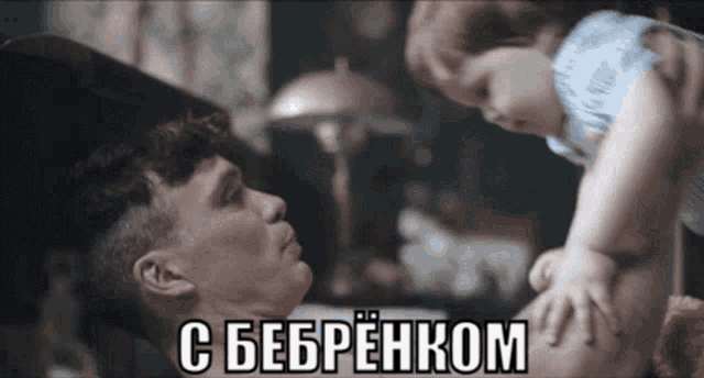a man is holding a baby in his arms and the baby is looking at the man in russian