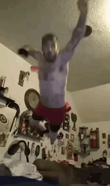 a shirtless man is jumping in the air with his arms outstretched