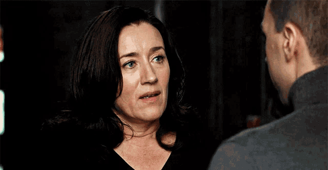 a man and a woman are looking at each other and the woman has a serious look on her face