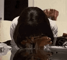 a woman is sitting on a couch drinking from a glass of water .