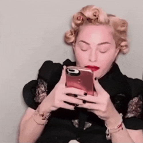 a woman with curlers in her hair is holding a cell phone in her hand .