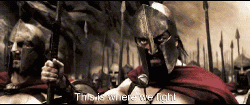 a man in a spartan helmet stands in front of a crowd of soldiers with the words `` this is where we fight ''