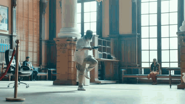 a man in a white shirt is kneeling down in a room