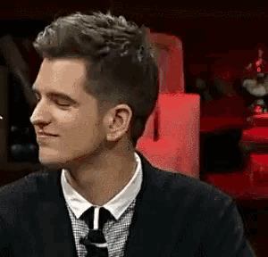 a man in a suit and tie is smiling in a dark room