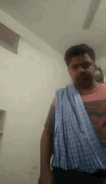 a man with a bandage on his arm is standing in front of a white wall .