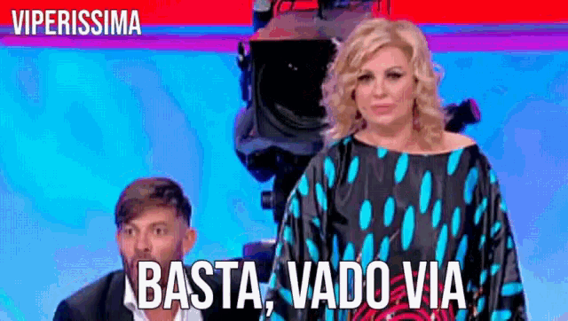 a woman in a polka dot dress stands next to a man in a suit and the words basta vado via
