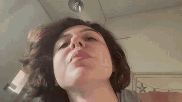 a close up of a woman 's face with a gray tank top on