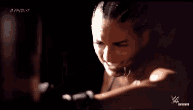 a woman is standing in a dark room with a boxing glove on her hand .