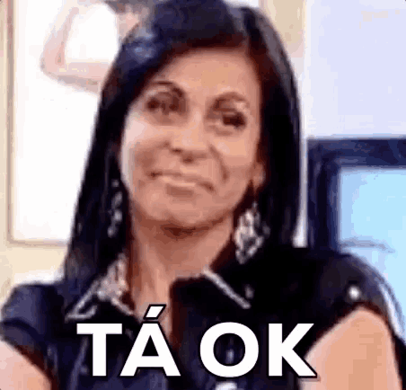 a woman is smiling and making a funny face with the words ta ok written on her face .