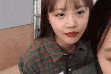 a girl in a plaid shirt with red lips looks at the camera