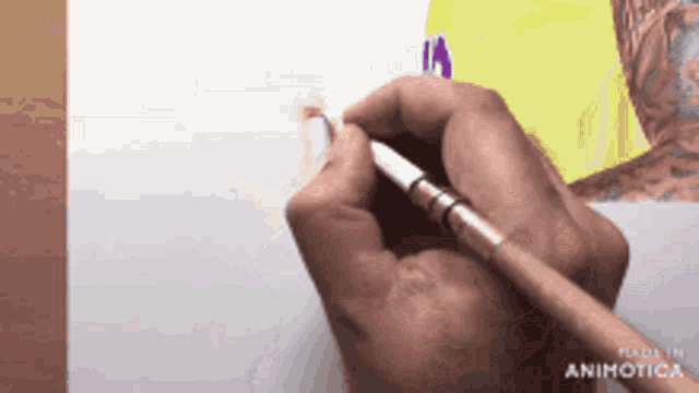 a person is holding a brush in their hand and drawing on a piece of paper
