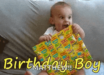 a baby is holding a birthday present with the words " birthday boy " written on it