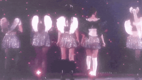 a group of girls are standing next to each other on a stage in front of a pink background .