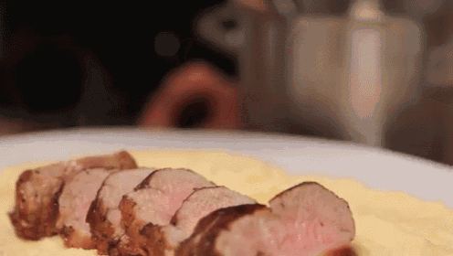 a close up of a plate of food with meat and mashed potatoes